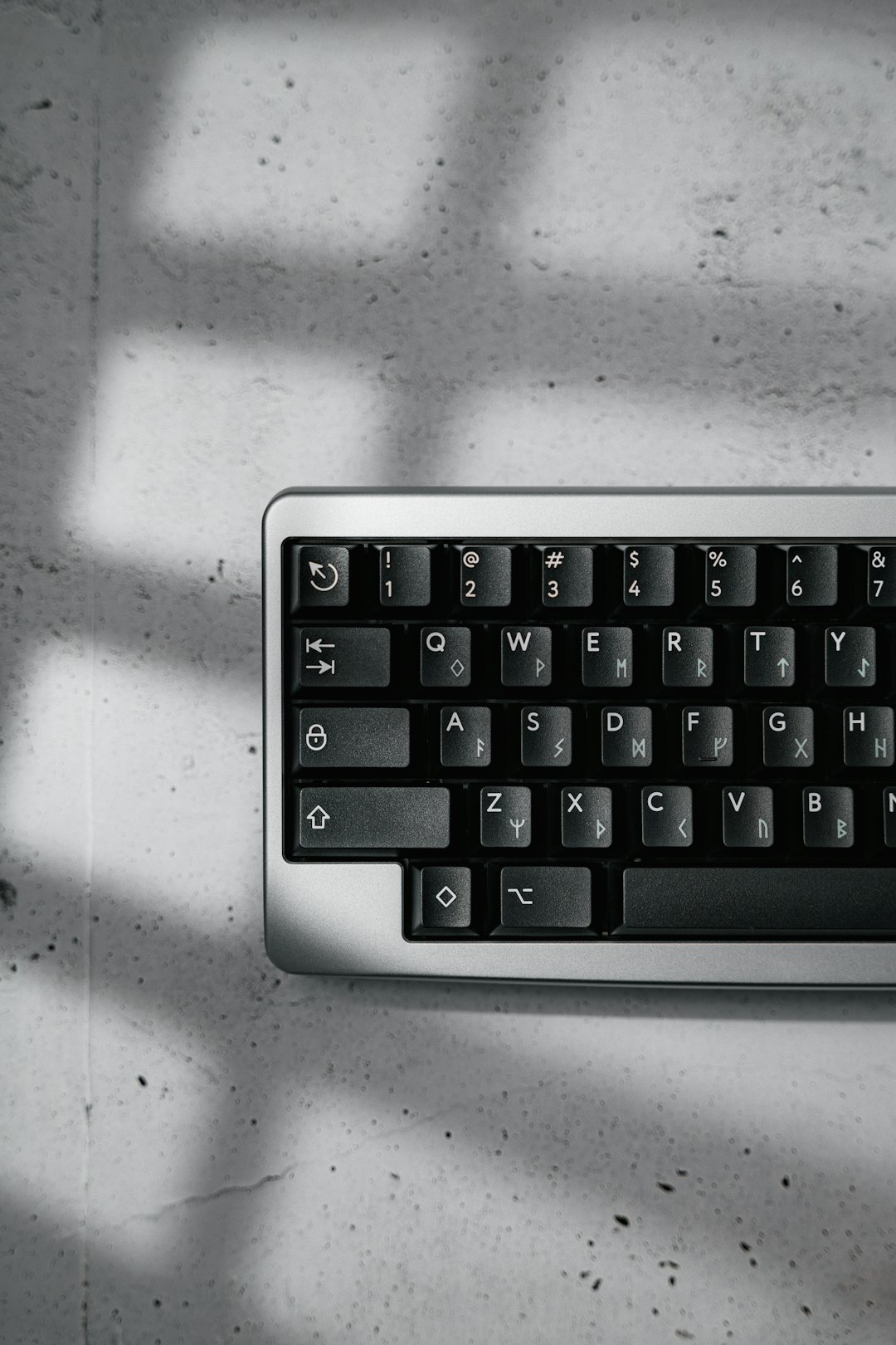 Mechanical keyboard with unique symbols resting on a concrete surface.